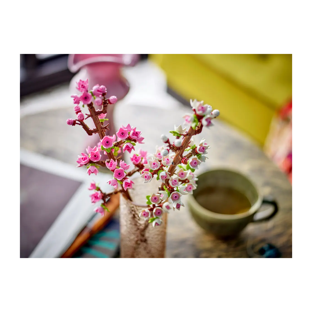 Two cherry blossom twig arrangements with pink and white buds displayed in a clear vase on a table.