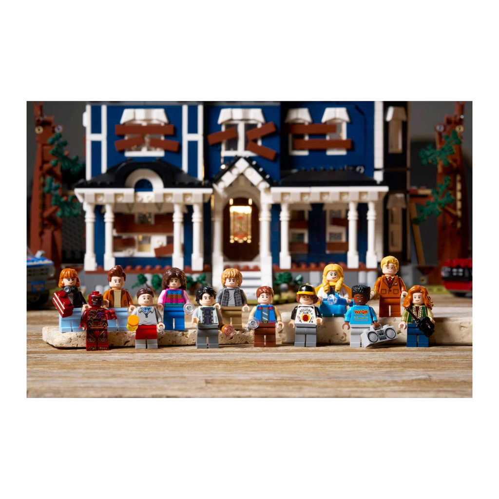 LEGO minifigures from Stranger Things in front of a detailed blue house with white trim and multiple windows.
