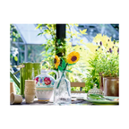Two vibrant LEGO Sunflowers in a clear vase with green stems, surrounded by decorative items and greenery.