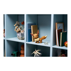 LEGO figure resembling a character with large ears and a bushy tail, displayed on a light blue shelf among decorative items.