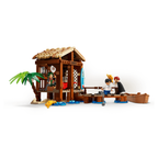 LEGO set featuring a windmill village hut, figures, a palm tree, and a small boat by a water feature.